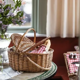 Picknickkorgen Ina i flätad pil med kylväska, packad för utflykt på ett köksbord.
