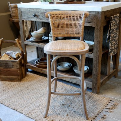 Fransk barstol med flätad rygg och sits från Chic Antique framför en rustik köksö.