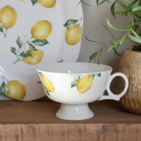 Cremevit kopp på fot Maison Citron från Chic Antique med solgula citroner i en trähylla.