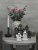 Two small white ceramic ghosts serving as candle holders, beautifully styled on a round wooden table in front of a rusty decorat