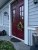 Warmly lit winter wreath on a classic deep red double front door of a country style house during evening twilight