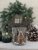 Stämningsfull ljuslykta Rustic Cottage från Majas Cottage med motiv av en julsnöklädd trästuga, vackert stylad på ett ljust träb