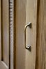 Close-up of a door and an antique brass handle on the Marseille bookcase in a natural finish, from Chic Antique.
