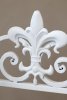 Detail shot of the fleur-de-lis that forms the crest of this antique-white shelf from Chic Antique.