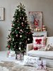 Rustic Christmas decor in a living room featuring a decorated Christmas tree, wrapped gifts, and a large iron Santa Claus sign on the wall.