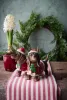 Two brown Christmas dachshunds in red dog sweaters and Santa hats standing on a red and white striped runner in front of a green