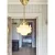Valter ceiling lamp with rod, brass and opal white hanging in a hallway - Strömshaga