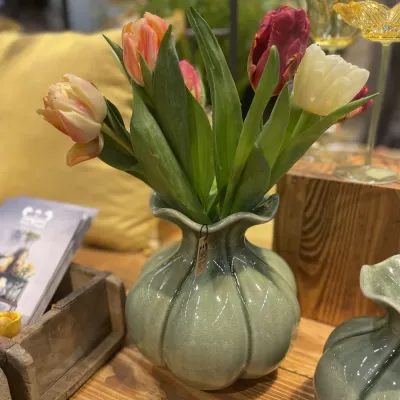 Grön vas med reaktiv glasyr i bullig form med tulpaner i mässmonter på Formex