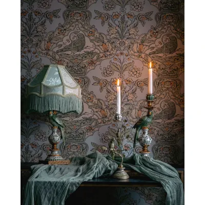 Papegojlampfot i grönt på ett bord mot en blommig tapet