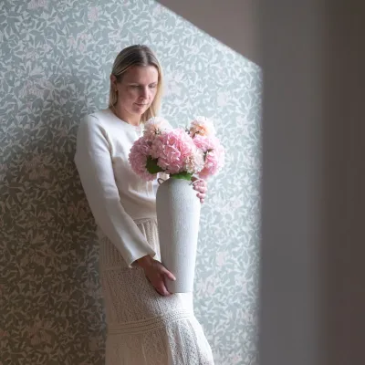 Rosa hortensior i vas som kvinna håller.