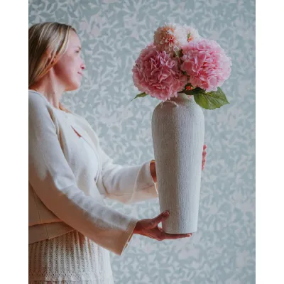 Kvinna med vas med rosa konstgjorda hortensior.