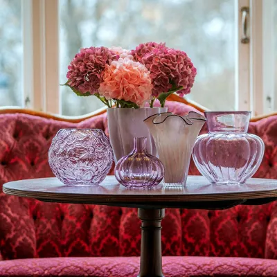 Rosa konstgjorda hortensior i vas på bord