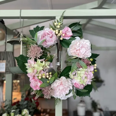 Fyllig blomkrans med rosa pion och hortensia på krok mot växthusstomme från A Lot Decoration