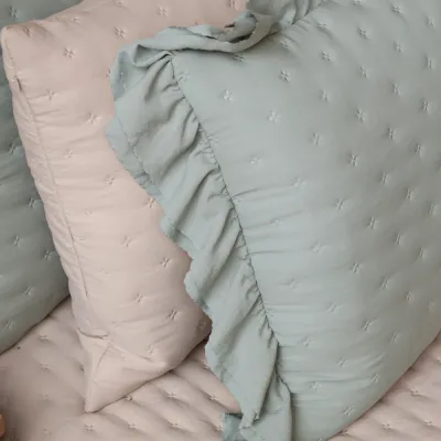 Närbild på detaljer, volang och broderi på dovt blågrönt kuddfodral Aix från Chic Antique