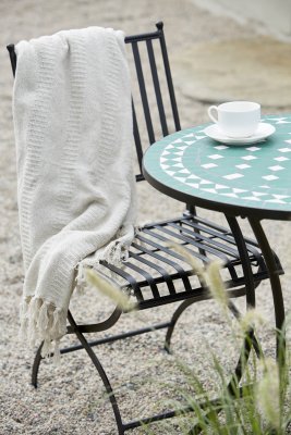 Lantlig trädgårdsinredning med svarta metallstolar på uteplats