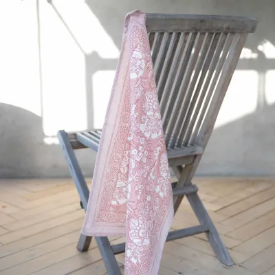 Kitchen towel Sonia in pink from Fondaco hanging on a chair.
