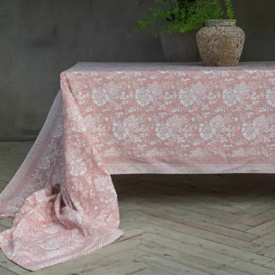 Large tablecloth Sonia in pink with a pattern from Fondaco laid on a table.