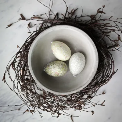 Grönmelerade påskägg från Wikholm Form att hänga som ligger i en skål på ett bord