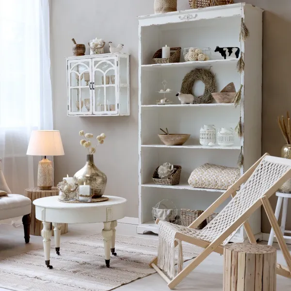 The Jacqueline bookcase in antique cream with a distressed patina, shown in a living room – from Chic Antique.