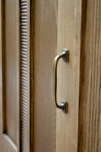 Close-up of a door and an antique brass handle on the Marseille bookcase in a natural finish, from Chic Antique.
