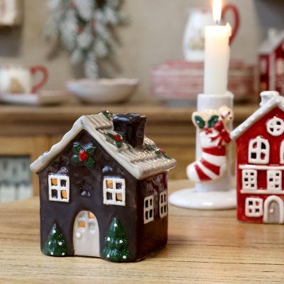 Handmålad ljuslykta i keramik föreställande ett julsnökläget litet hus i mocca från Chic Antique på ett rustikt träbord bredvid