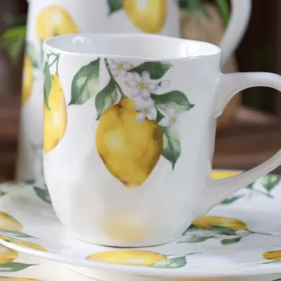 Porslinsmugg i cremevitt med solgula citroner på en assiett från Chic Antique.