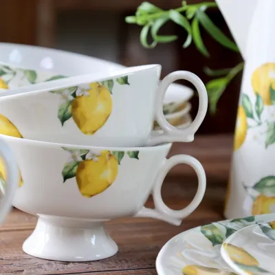 Närbild på den cremmevita koppen Maison Citron från Chic Antique på ett träbord.