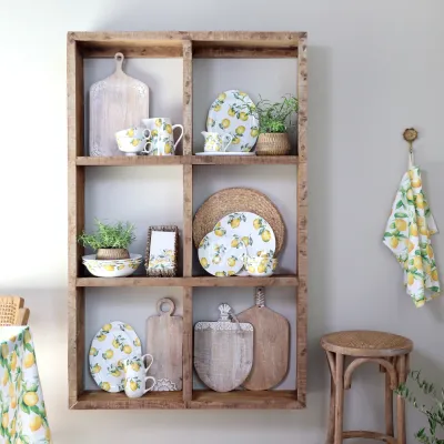Flera delar av porslinsserien Maison Citron från Chic Antique i en trähylla.
