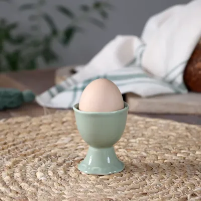Äggkoppen Provence i Verte – ljusgrön från Chic Antique på ett bord med ett ägg i.