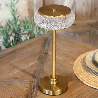 Celine uppladdningsbar bordslampa i antikmässing på ett dukat bord.