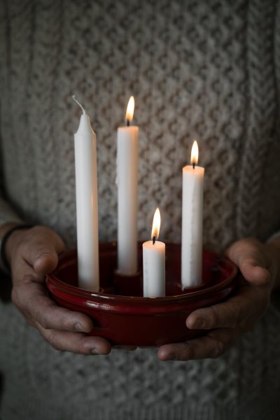 Röd adventsljusstake med tre tända ljus händerna på Ernst.