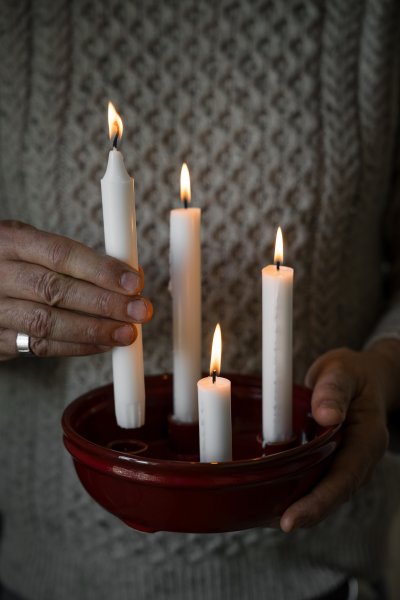 Rös ljusstake med fyra tända ljus på ett bord, från Ernst