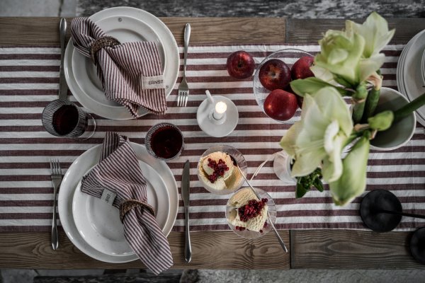 Dukat julbord taget ovanifrån med rödrandiga textilier från Ernst på ett rustikt bord.