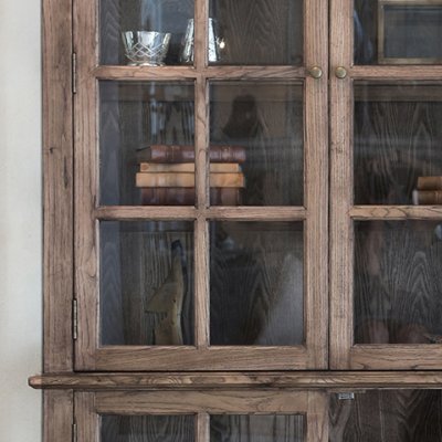 Närbild på spröjsad glasdörr till Marseille vitrinskåp i naturträ med klassiska knopphandtag.